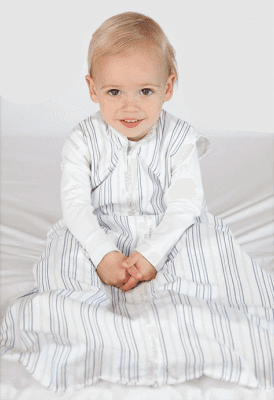 Joey Swag Baby Sleeping Bag on a smiling toddler sitting on a bed, showcasing its lightweight design.