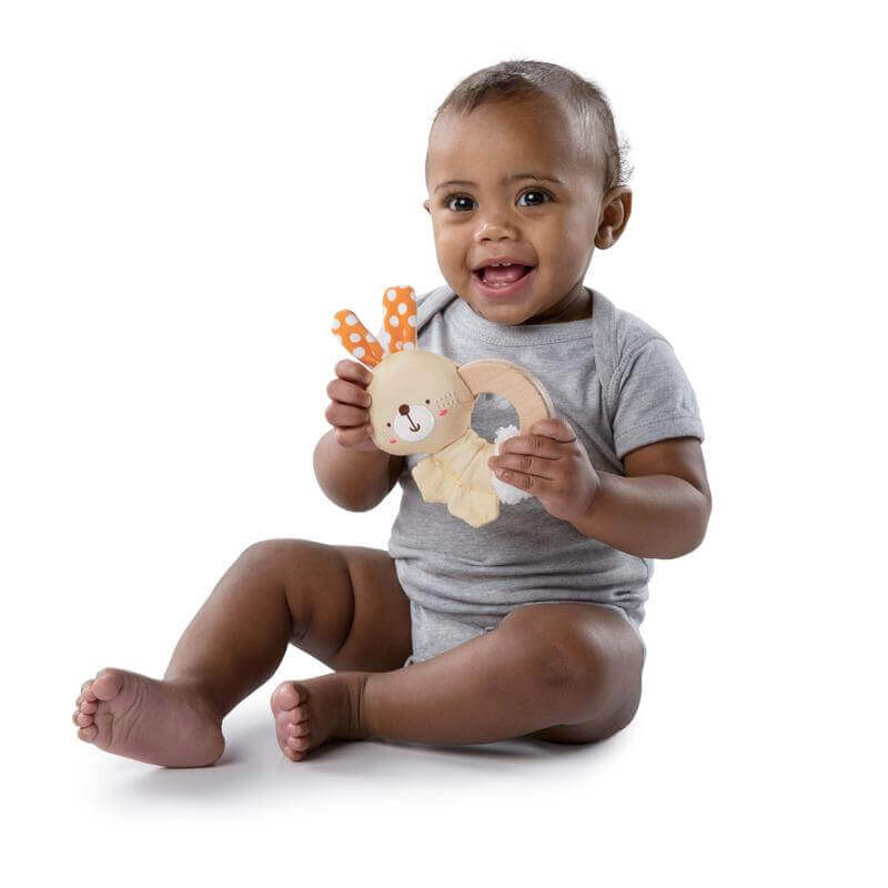 Baby happily holding Clutch and Hold Wood Toy Bunny with a smiling face, showcasing engagement and playfulness.